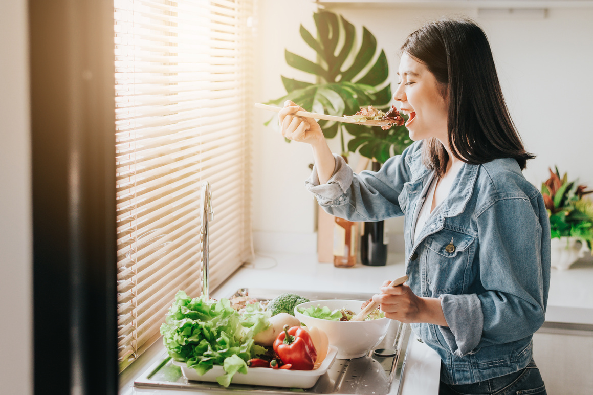 Happy Woman Eating Healthy Fresh Vegetables Salad in Kitchen